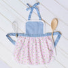 Baby and toddler apron with lace trim, flat lay with wooden spoon