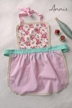 Lace apron for girls in red, worn by a child