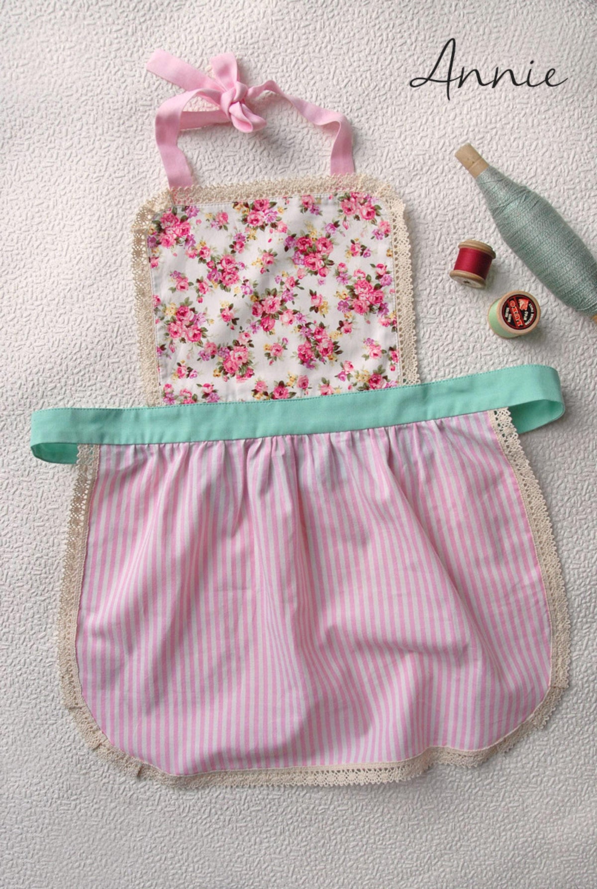 Lace apron for girls in red, worn by a child